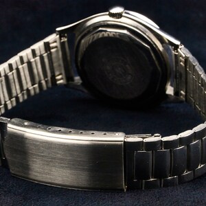 May include: A silver wristwatch with a metal band. The watch face is not visible, but the back of the watch is visible.
