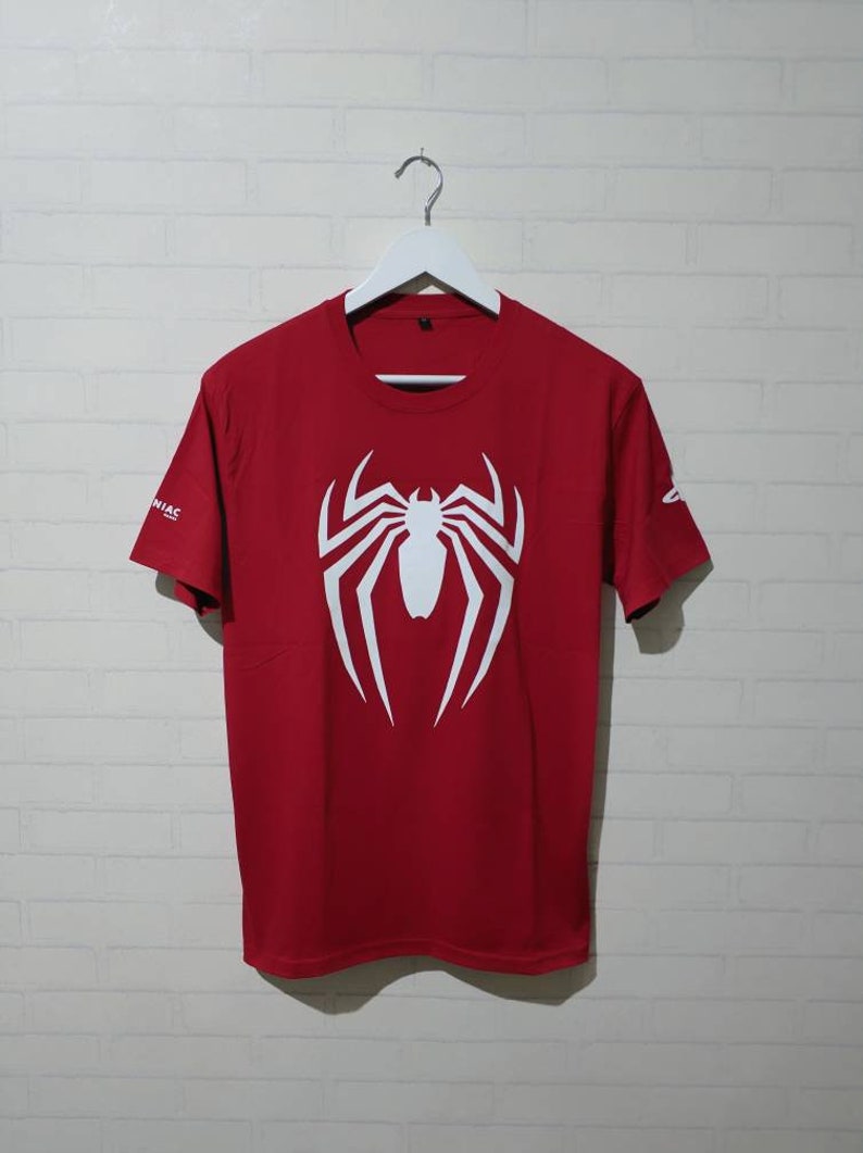 May include: Red t-shirt with a white spider-man logo on the front.