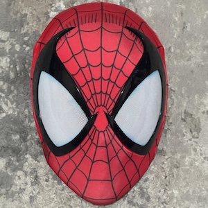 Op de afbeelding: Een rood Spider-Man masker met een zwart webpatroon en zwarte oogomrandingen. De oogopeningen zijn wit met een mesh textuur. Het masker is een volledige gezichtsbedekking, waarschijnlijk voor cosplay of kostuimgebruik.