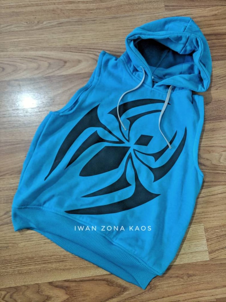 Puede incluir: Una sudadera azul sin mangas con un dise&ntilde;o tribal negro y el texto "Iwan Zona Kaos" en la parte delantera.
