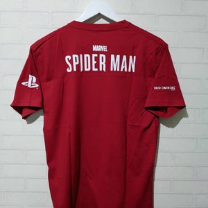 May include: Red t-shirt with white text that says "MARVEL SPIDER-MAN" on the back and "INSOMNIAC" on the right sleeve. The PlayStation logo is on the left sleeve.