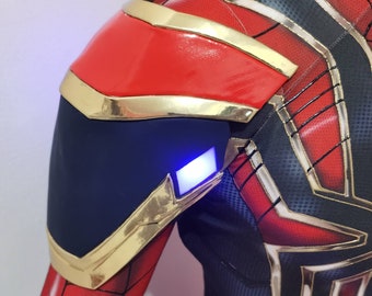 Può includere: Un costume da supereroe rosso e nero con dettagli dorati. Il costume ha una luce blu sulla spalla.