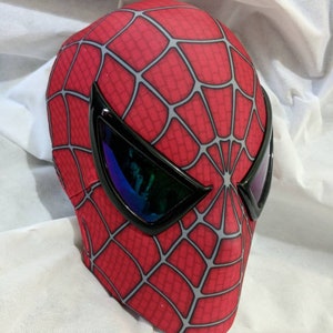 May include: A red and grey Spider-Man mask with black eye holes and a black plastic visor.