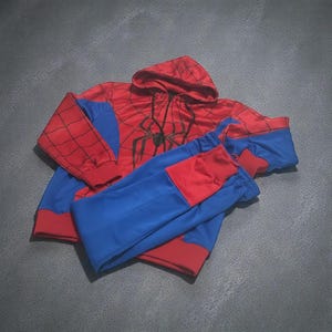 May include: A Spider-Man costume set in red and blue, comprising a hooded sweatshirt and trousers. The sweatshirt has a black spider emblem and web design. The trousers are blue with red cuffs.