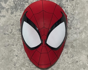 Könnte beinhalten: Eine rote Spider-Man-Maske mit schwarzem Spinnennetz-Muster und schwarzen Augenrändern. Die Augen sind weiß mit einem Netzmuster. Diese Vollmaske ist für Kostüme oder Cosplay gedacht.