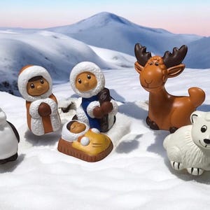Puede incluir: Un conjunto de figuras con temática invernal, que incluye un pingüino, un oso polar, un alce y figuras con ropa de invierno. Las figuras están colocadas sobre un fondo nevado con una cordillera al fondo. Las figuras son de material brillante.