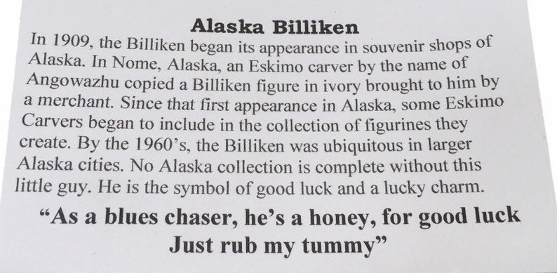 May include: A white card with black text about the history of the Billiken in Alaska. The text includes the quote "As a blues chaser, he's a honey, for good luck Just rub my tummy."