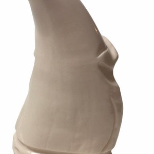 May include: White ceramic figurine of a gnome with a pointed hat. The gnome is wearing a long, flowing robe and has a beard.