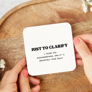 May include: White coaster with black text that reads "JUST TO CLARIFY I THINK YOU MISUNDERSTOOD, AND IT'S DEFINITELY YOUR FAULT"
