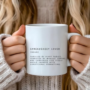 May include: White ceramic mug with black text that reads "Spreadsheet Lover (Noun) Thrilled by pivot tables, terrified by #VALUE! errors, and convinced life itself would improve with conditional formatting."