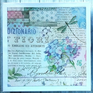 May include: A square canvas wall art piece featuring a collage of vintage-style Italian text, hydrangea flowers in shades of blue and purple, and a dragonfly illustration. The design includes script handwriting, postal stamps, and floral patterns.