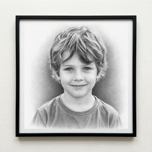 May include: A framed pencil portrait of a young child with curly hair, wearing a grey t-shirt. The portrait is in a black frame and is displayed against a white background.