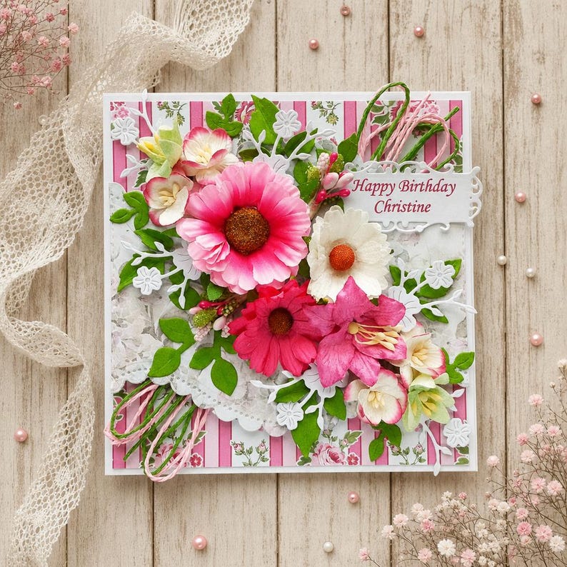 Pu&ograve; includere: Un biglietto d'auguri quadrato con uno sfondo a righe rosa e bianche con motivi floreali. Il biglietto &egrave; decorato con fiori di carta a strati nelle tonalit&agrave; del rosa, bianco e verde, e un'etichetta bianca con il testo Happy Birthday Christine.