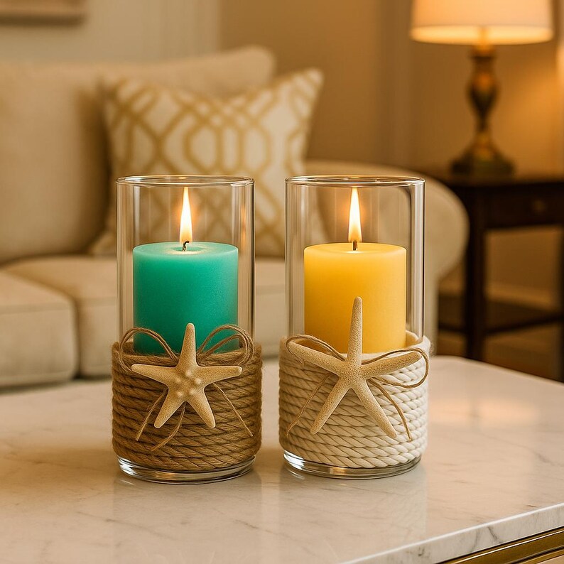 May include: Two cylindrical glass candle holders, each containing a lit pillar candle. One candle is teal with a brown rope wrap and a beige starfish. The other candle is yellow with a white rope wrap and a beige starfish attached to the front.