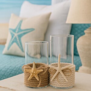 May include: Two clear glass cylindrical candle holders. One is wrapped in brown jute twine with a tan starfish and a small twine bow. The other is wrapped in cream-colored rope with a white starfish and a matching cream-colored rope bow.