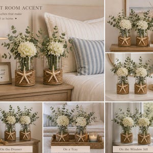 May include: Two clear glass cylindrical vases wrapped in thick tan jute rope, each featuring a single beige starfish centered on the front. The vases are filled with white hydrangea flowers and green eucalyptus stems, creating a floral arrangement.