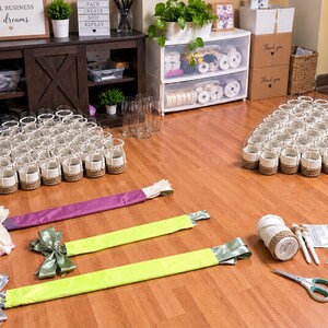 a room with various craft supplies and materials, including baskets, ribbons, scissors, and other decorative items. The room appears to be a workspace or storage area, with a wooden floor and a shelf with additional supplies.