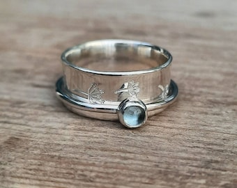 An Aquamarine and dandelion spinner ring.