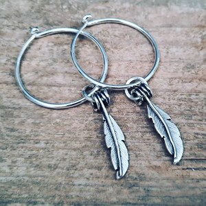 Silver feathers on hoop earrings.