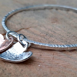 Line textured bangle with a silver and a copper heart.