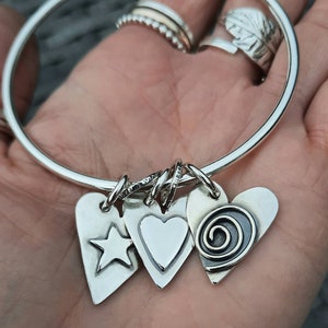 A silver bangle with double sided silver hearts and a Paua Shell.