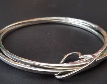 A Stunning trio of interlinked silver bangles with a silver heart.