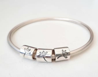 A gorgeous chunky silver bangle with three dandelion stamped rings.