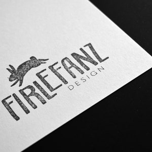 May include: A black and white logo with the text "Firlefanz Design" and a stylized image of a rabbit jumping.