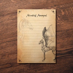 Könnte beinhalten: Ein liniertes Notizbuch mit einem Vintage-Pergamentpapier-Aussehen. Es zeigt eine Illustration eines skelettartigen, geflügelten Wesens und den Text "Mischief Managed" in eleganter Schrift. Dekorative Eckverzierungen tragen zur antiken Ästhetik bei.