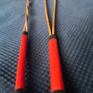 May include: Two red and black whips with brown leather handles.