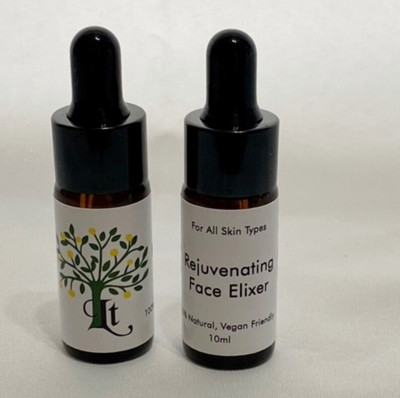 May include: Two small brown glass bottles with black dropper tops and white labels. The label on the right bottle reads "For All Skin Types Rejuvenating Face Elixir 100% Natural, Vegan Friendly 10ml".