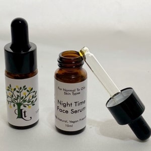May include: Two amber glass bottles with black dropper tops. The bottle on the right has a dropper attached. Both bottles have white labels with a green tree and the text "It" and "Night Time Face Serum". The label on the right bottle also includes the text "For Normal To Oily Skin Types", "100% Natural, Vegan Friendly", and "10ml".