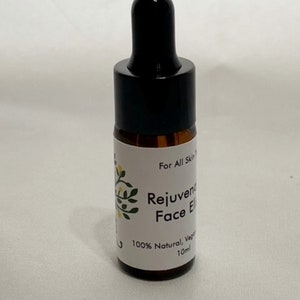 May include: A small brown glass bottle with a black dropper top. The label reads "For All Skin Types, Rejuvenating Face Elixir, 100% Natural, Vegan, 10ml."