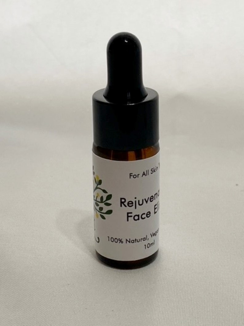 May include: A small brown glass bottle with a black dropper top. The label reads "For All Skin Types, Rejuvenating Face Elixir, 100% Natural, Vegan, 10ml."
