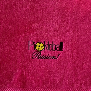 May include: Pink towel with black embroidered text that reads "Pickleball! Passion!" and a yellow pickleball graphic.