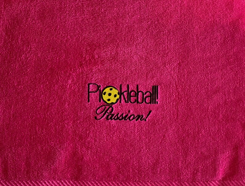 May include: Pink towel with black embroidered text that reads "Pickleball! Passion!" and a yellow pickleball graphic.