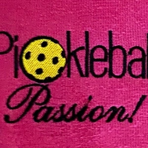 May include: Pink towel with black embroidery that reads "Pickleball! Passion!" with a yellow pickleball in the center.