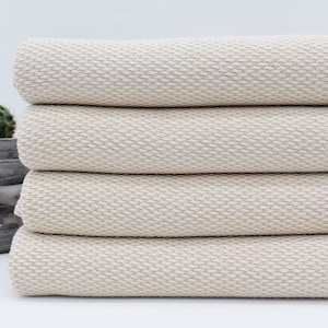 May include: A stack of four cream-coloured Turkish towels with a waffle weave texture.