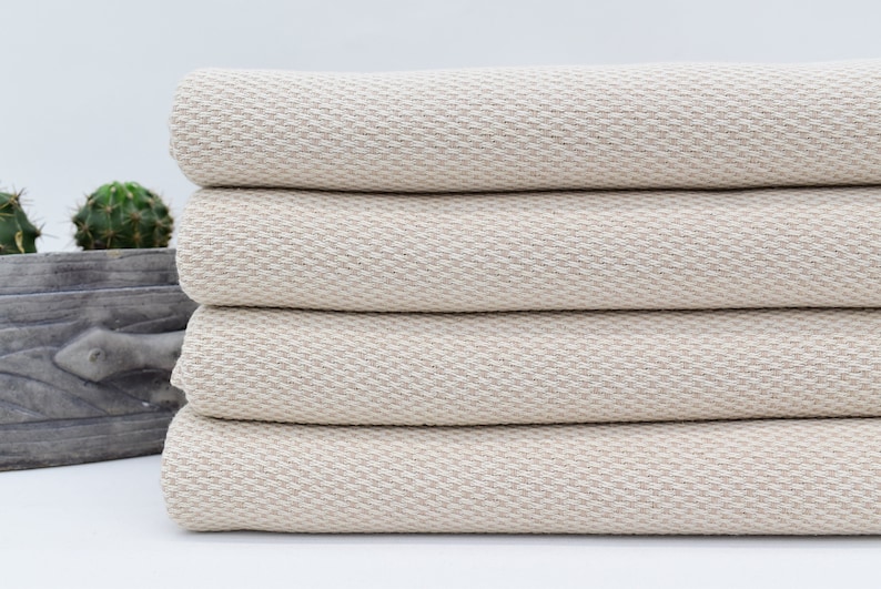 May include: A stack of four cream-coloured Turkish towels with a waffle weave texture.
