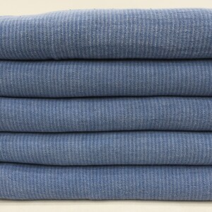 May include: A stack of five blue waffle weave towels. The towels are folded and stacked on top of each other.