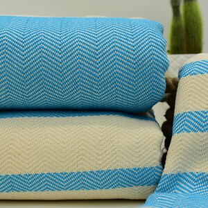 May include: A stack of two blue and white striped towels with a chevron pattern. The towels are folded and stacked on top of each other.
