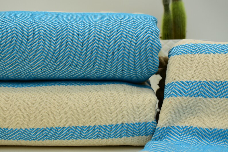 May include: A stack of two blue and white striped towels with a chevron pattern. The towels are folded and stacked on top of each other.