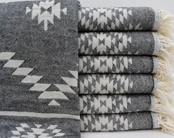 May include: A stack of black and white patterned towels with fringe edges. The towels have a geometric design.