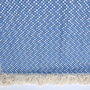 May include: A blue and white checkered throw blanket with a fringe border. The blanket is folded and displayed with other blankets in various colors.