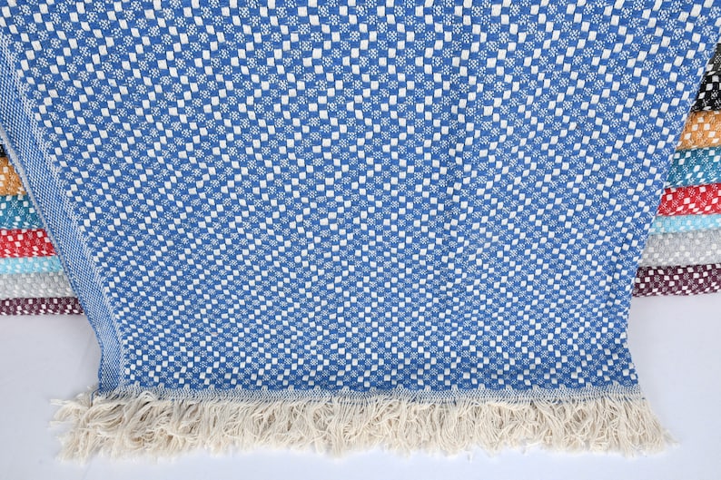 May include: A blue and white checkered throw blanket with a fringe border. The blanket is folded and displayed with other blankets in various colors.