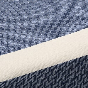 May include: A blue and white striped Turkish towel with a diamond pattern. The towel is made of cotton and is soft and absorbent.