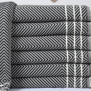 May include: A stack of black and white striped towels with fringe edges. The towels are folded and stacked on top of each other.
