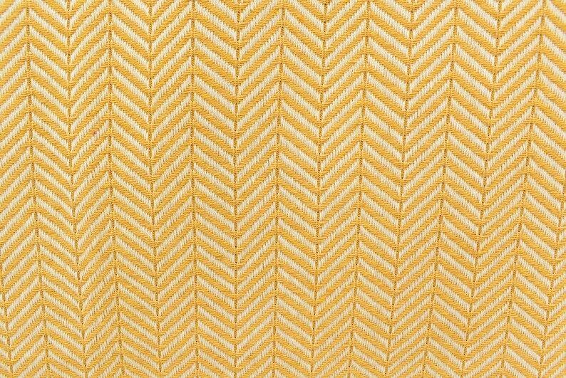 Op de afbeelding: Gele en witte stof met chevron-patroon en een geweven textuur.