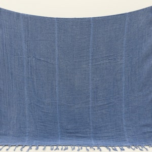 May include: A blue cotton throw blanket with fringe on the bottom edge.