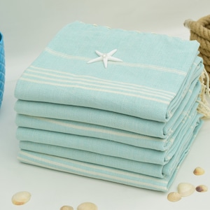 May include: A stack of light blue and white striped Turkish towels with a white starfish on top.